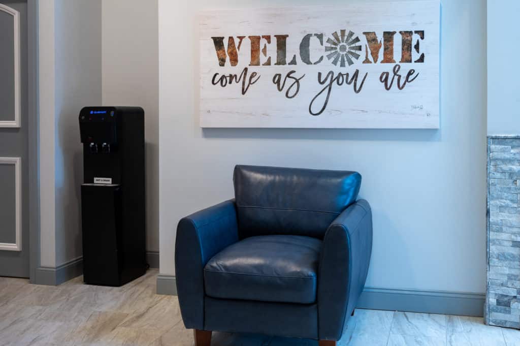 Photo showing chair with decorative sign saying welcome come as you are