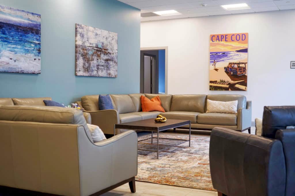 photo showing patient common area in detox with couches decorative paintings and rug