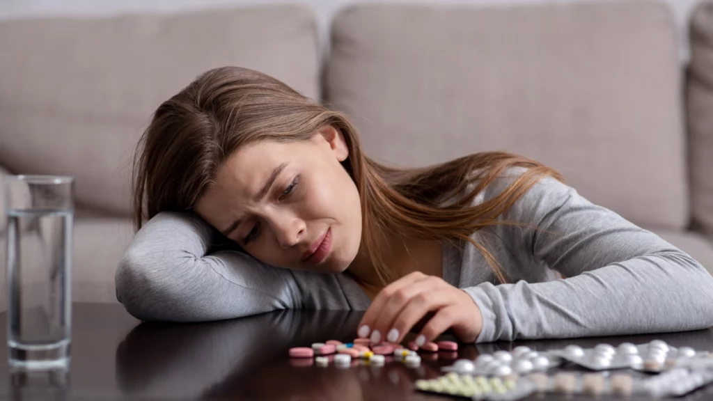 depressed woman looking at pills on a table