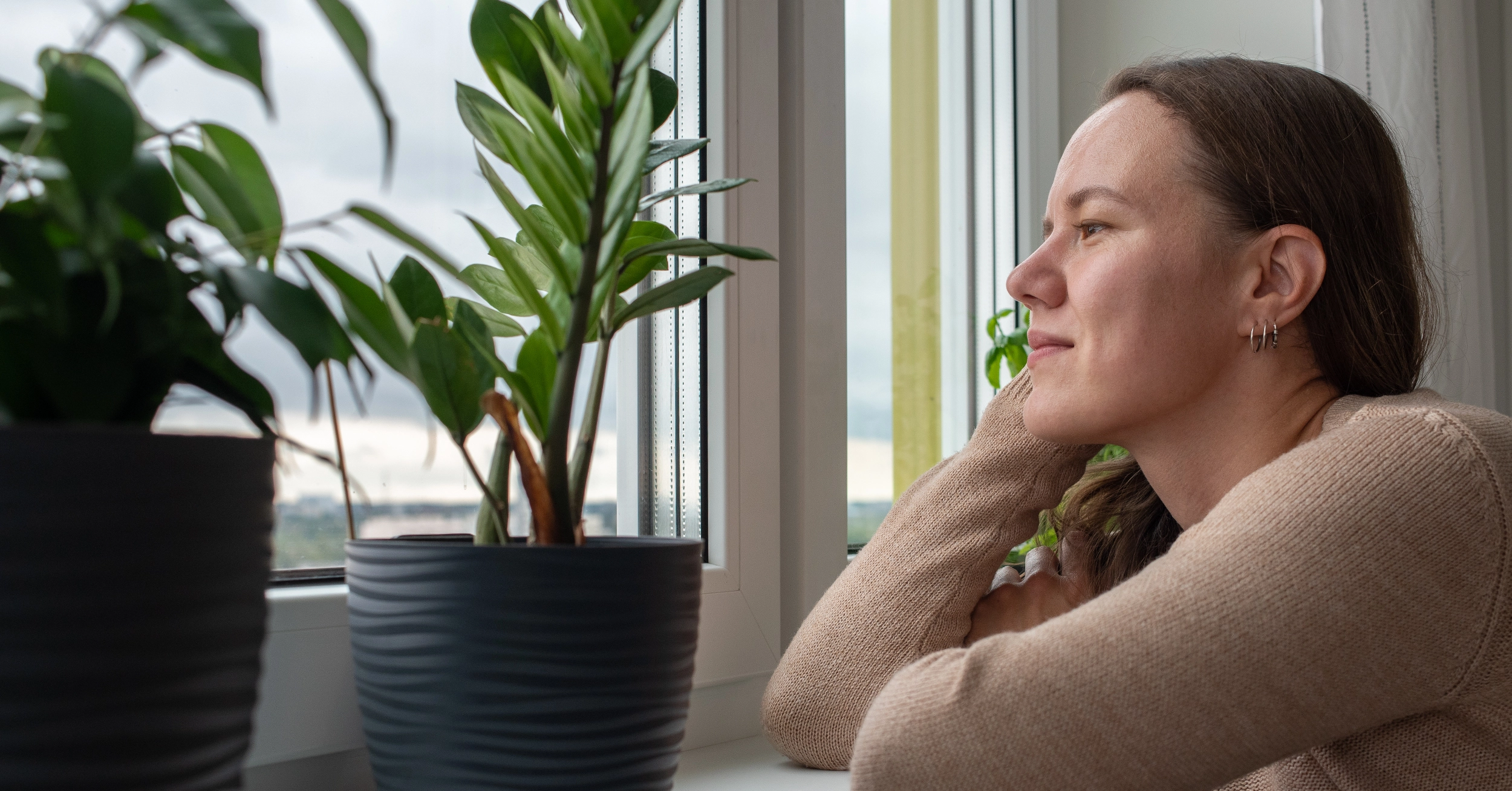 Woman smiling and looking out of a window. White text explains drug and alcohol detox is a critical first step in addiction treatment.