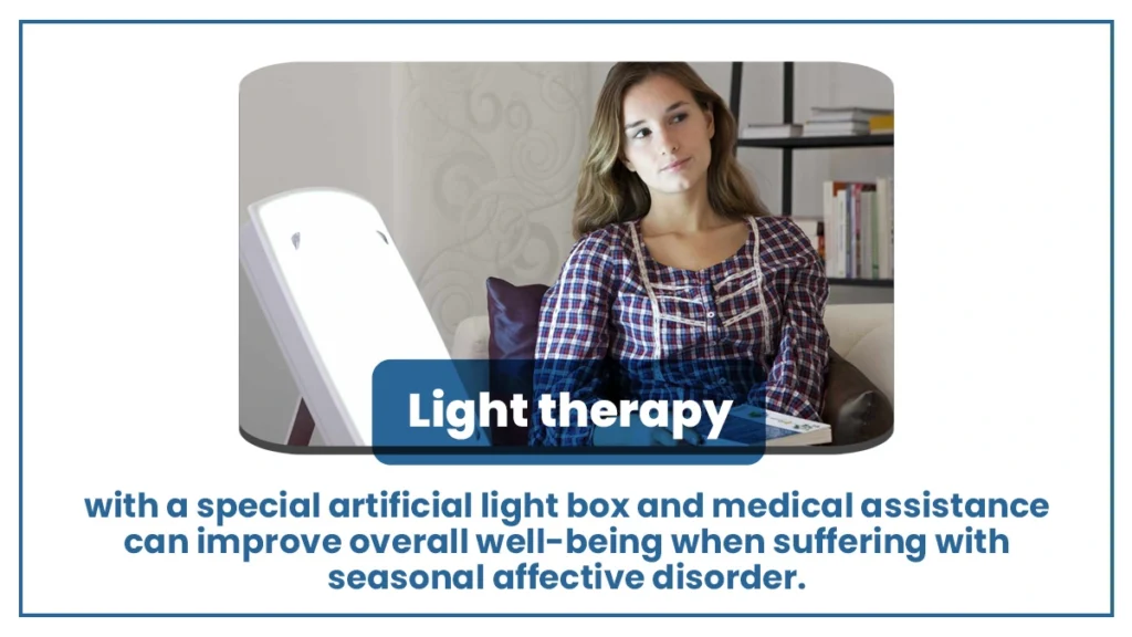 Woman sitting alone in front of a light therapy box with a book in her lap. Light therapy treats seasonal affective disorder. 