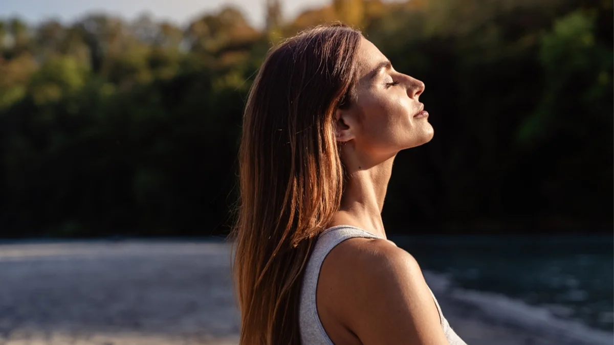 woman with sunlight shining on her face as she looks upward