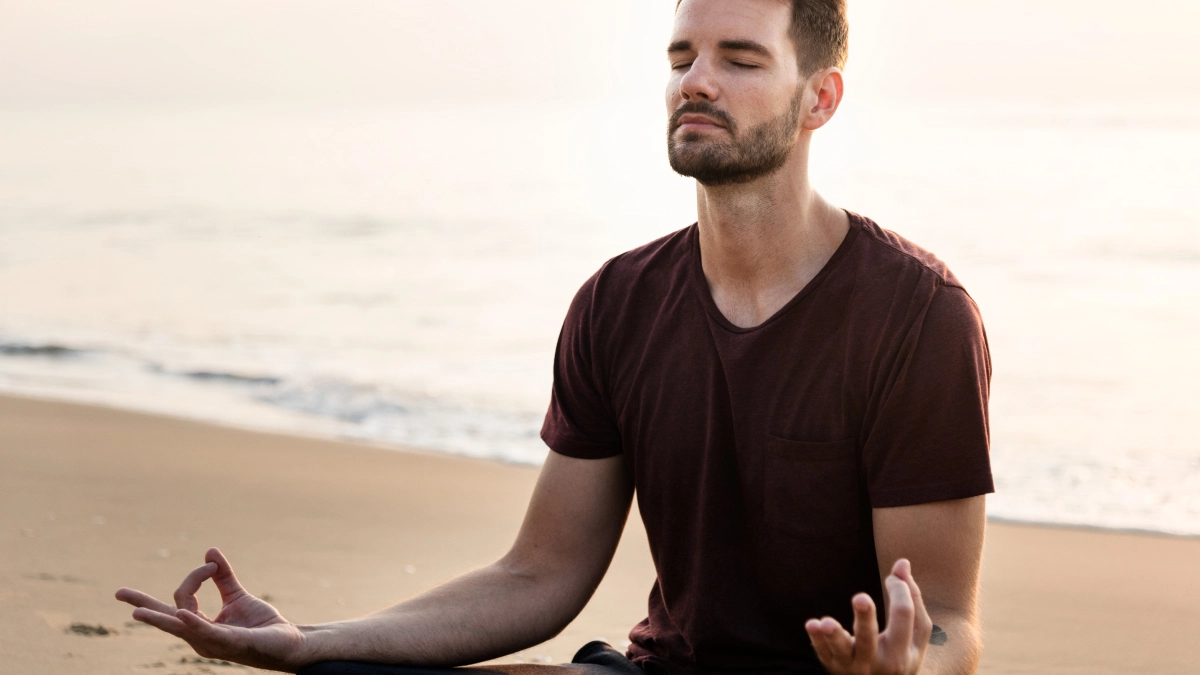 man meditating on a beach