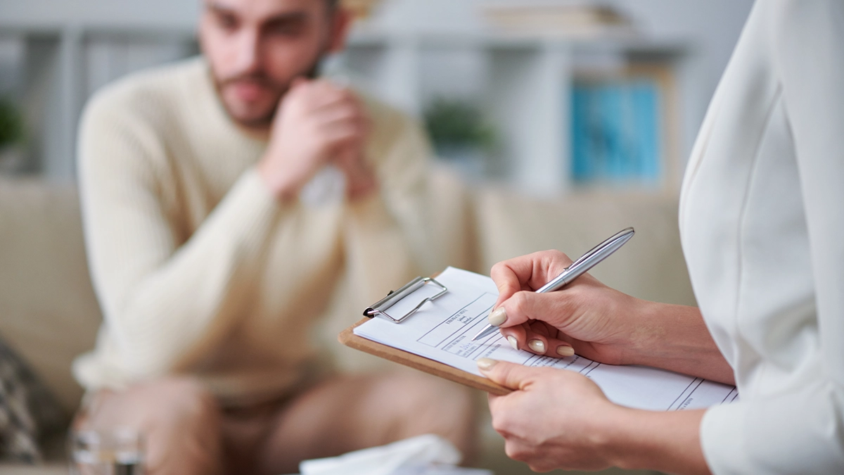 A close-up of a healthcare professional's hands as they write on a clipboard during a session.